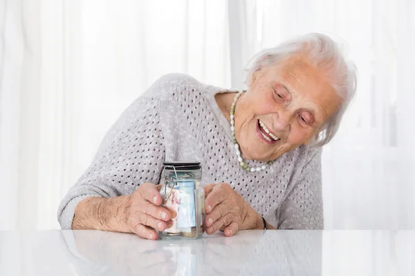 Heureuse femme âgée regardant pot d'argent — Photo