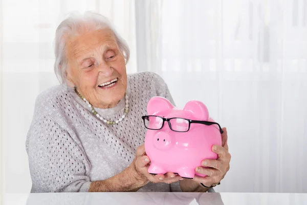 Seniorin hält Sparschwein — Stockfoto