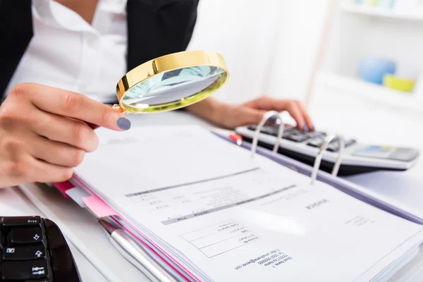Kadın muhasebeci faturaları analiz etmek için Büyüteç tutarak — Stok fotoğraf