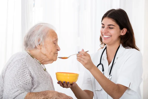 Medico che alimenta la minestra al paziente anziano — Foto Stock