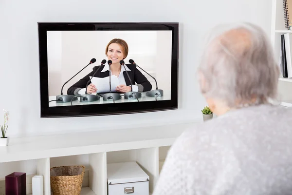 Mormor titta på nyheterna på teve — Stockfoto