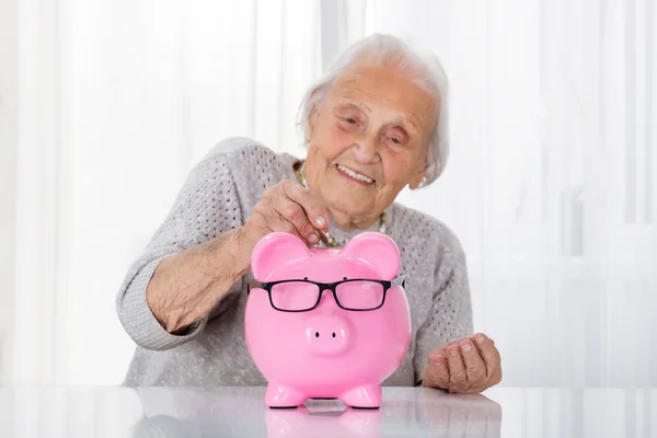 Seniorin wirft Münze ein — Stockfoto