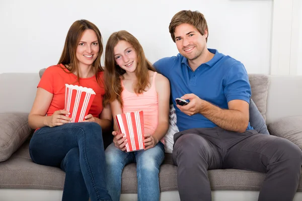 Famiglia seduta sul divano a guardare la televisione — Foto Stock