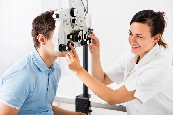 Optometrista femenina haciendo pruebas visuales para el paciente Imágenes de stock libres de derechos