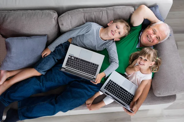 Семья с ноутбуком и цифровым планшетом дома — стоковое фото