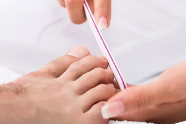 Manicurist gør trimning af mandlige tånegle - Stock-foto