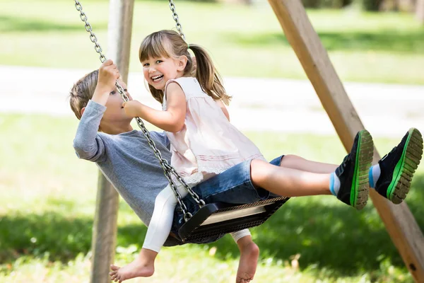 Två barn på swing — Stockfoto