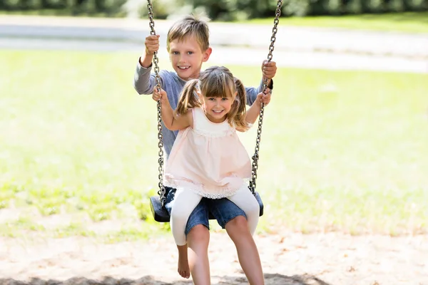 Två barn på swing — Stockfoto