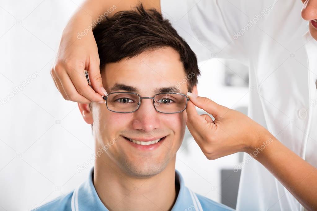 Optician Helping Man With New Eyeglasses