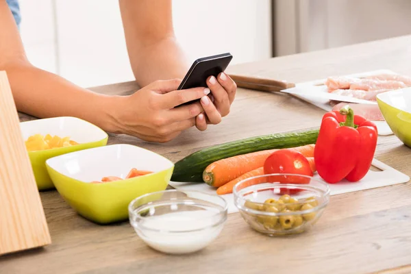 Жінка використовує смартфон на кухні — стокове фото