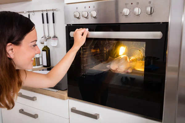 Mujer asando pollo en el horno — Foto de Stock