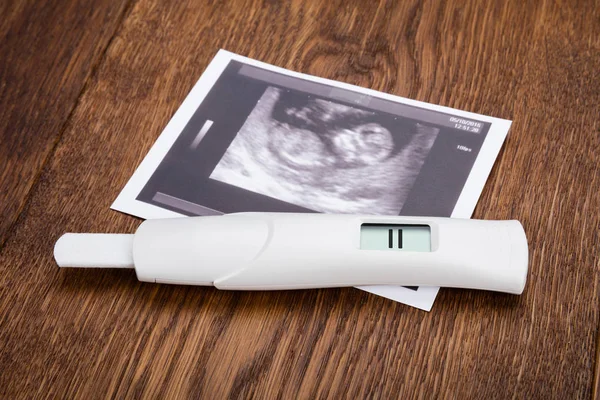 Pregnancy test on wooden desk — Stock Photo, Image