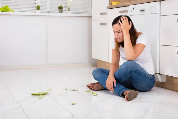 Frau blickt auf zerbrochenen Teller am Boden — Stockfoto
