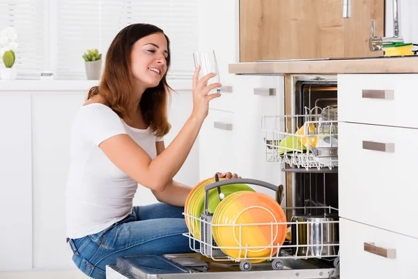 Женщина берет стакан из посудомоечной машины — стоковое фото