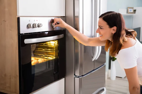 Mulher usando forno na cozinha — Fotografia de Stock