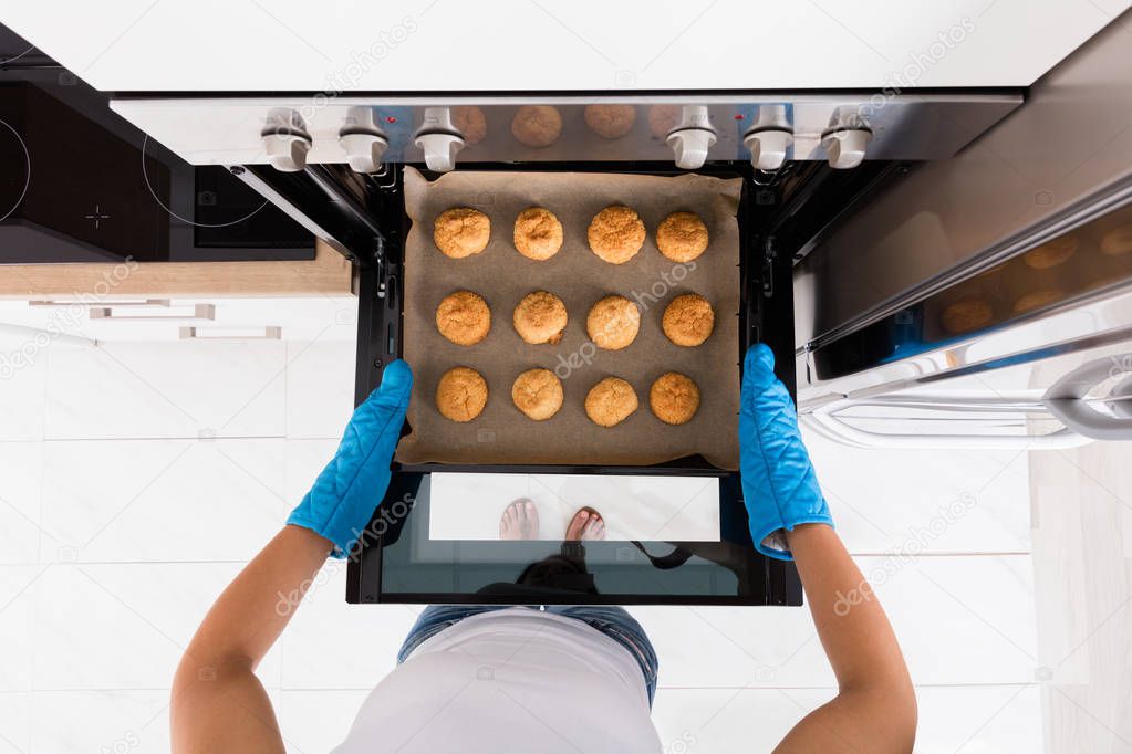 Woman baking cookies in oven