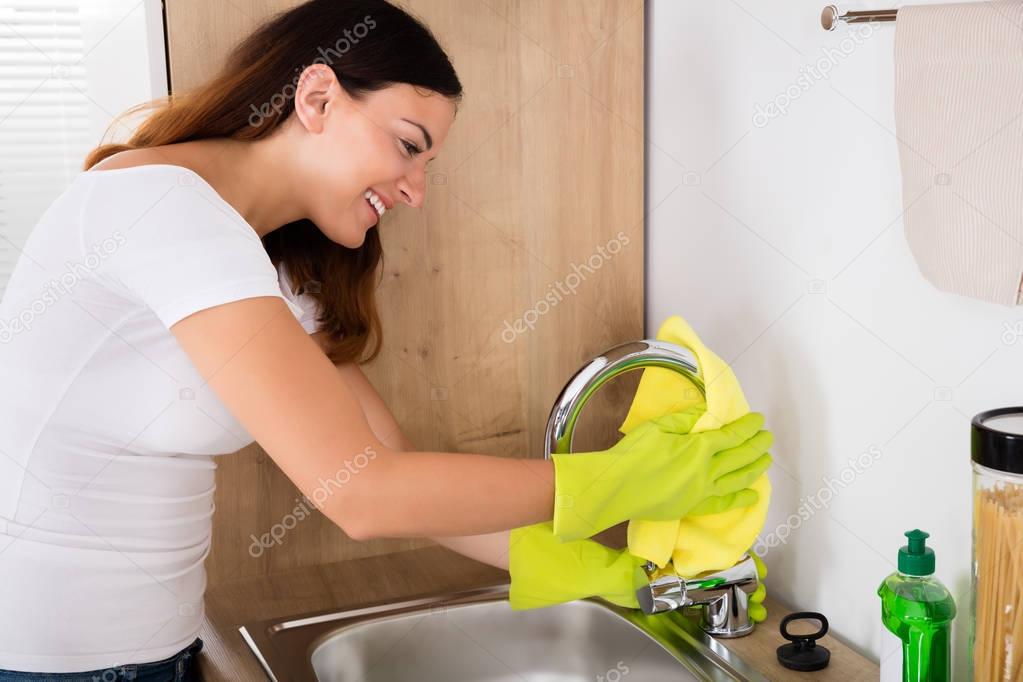 Happy female cleaning tap