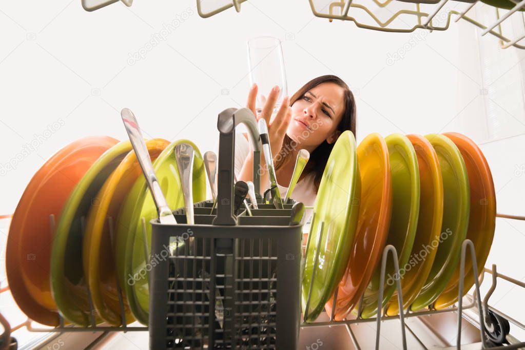Woman looking at glass in dishwasher
