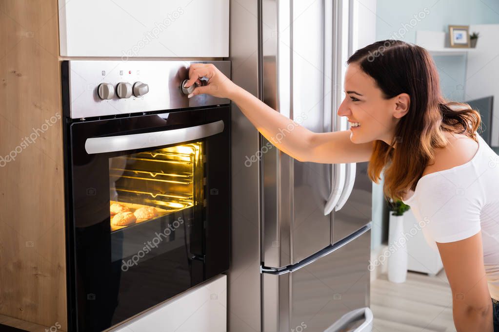 Woman using oven in kitchen