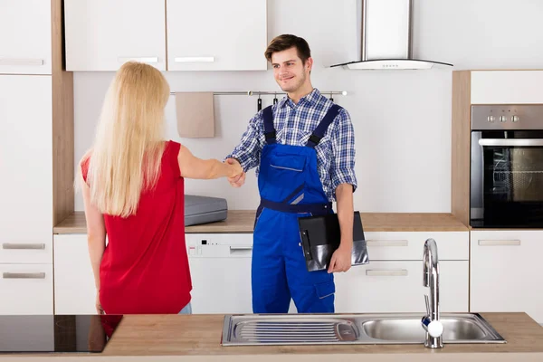 Vrouw schudden handen met loodgieter — Stockfoto