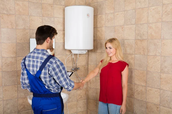 Mujer sacudiendo las manos con fontanero — Foto de Stock