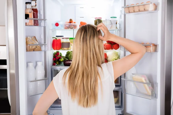 Frau schaut in Kühlschrank — Stockfoto