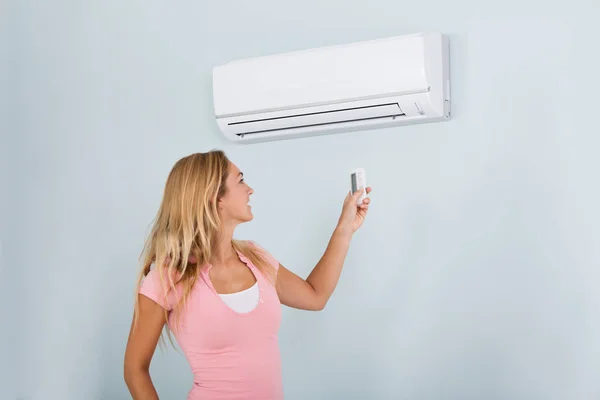 Woman Operating Air Conditioner — Stock Photo, Image