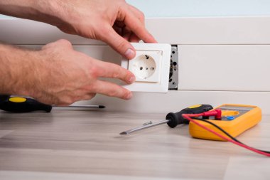 Person Installing Socket On Wall clipart