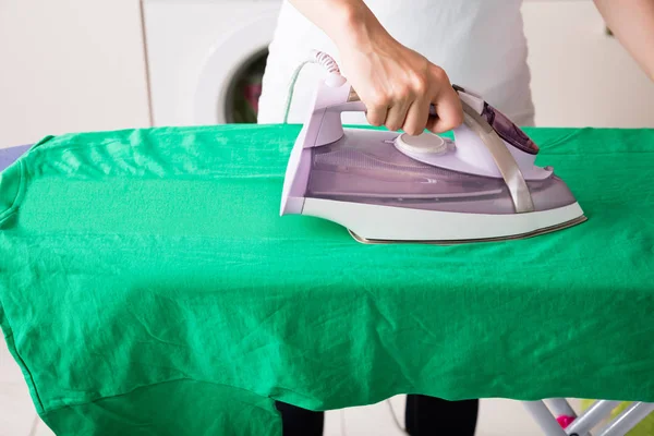 Frau bügelt grünes T-Shirt — Stockfoto