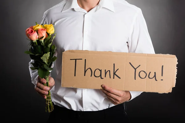 Hombre sosteniendo rosas y cartón — Foto de Stock