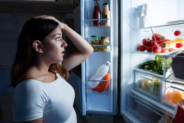 Kvinna som tittar på öppna kylskåp — Stockfoto