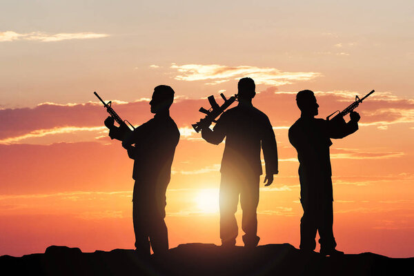 Силуэты солдат с винтовками
