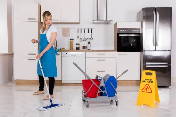 Vrouw schoonmaak keukenvloer — Stockfoto