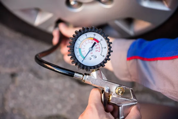 Pessoa que mede a pressão do pneu do carro — Fotografia de Stock