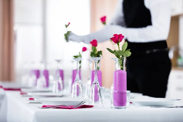 Официант устраивает розы в вазах — стоковое фото