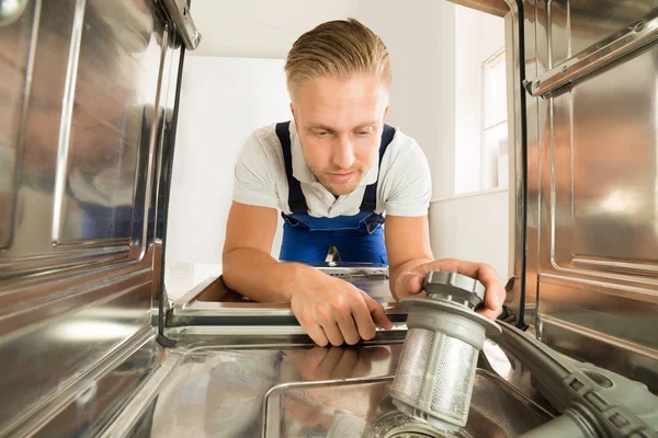 Человек чинит посудомоечную машину — стоковое фото