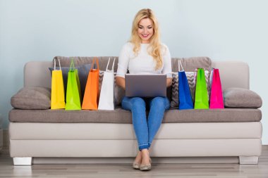 dizüstü bilgisayar kullanan gülümseyen kadın