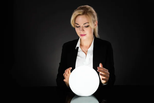 Donna d'affari guardando sfera di cristallo — Foto Stock