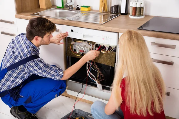 Техник мужского пола проверяет посудомоечную машину — стоковое фото