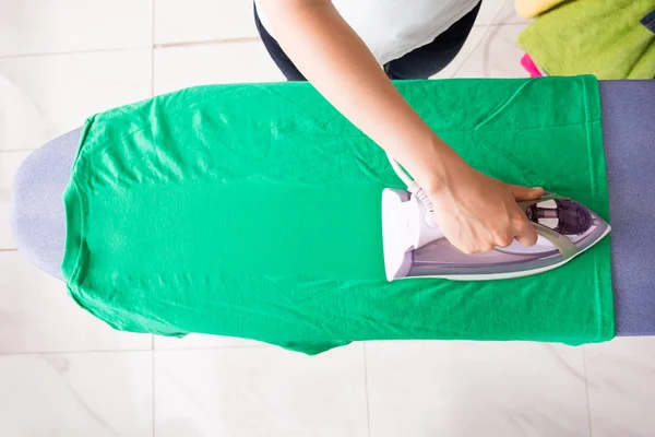 Mulher de engomar camisa verde — Fotografia de Stock
