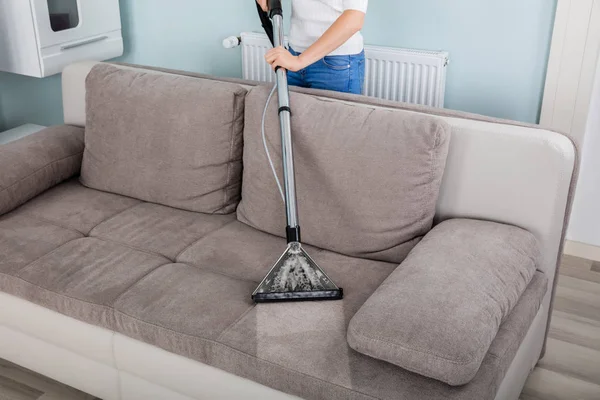 Frau putzt Sofa mit Staubsauger — Stockfoto