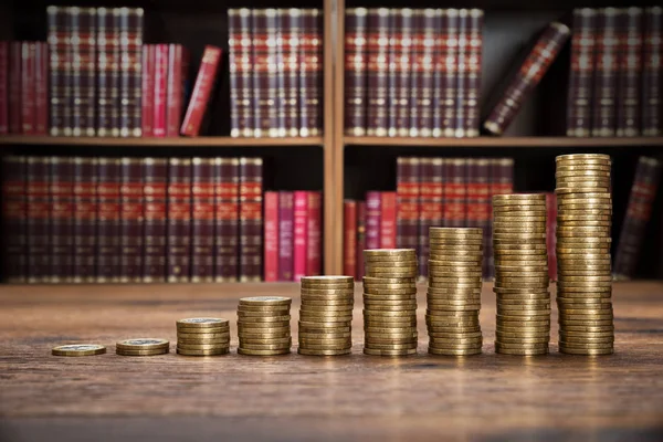 Monedas apiladas en escritorio de madera — Foto de Stock