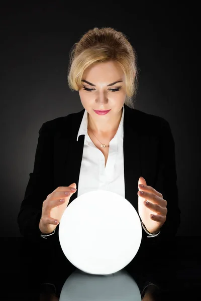 Donna d'affari guardando sfera di cristallo — Foto Stock