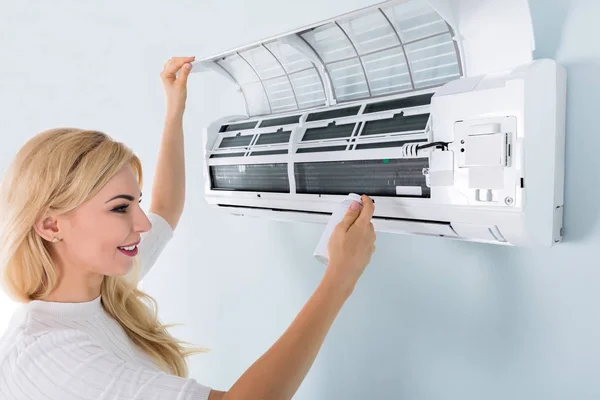 Vrouw schoonmaken airconditioner — Stockfoto