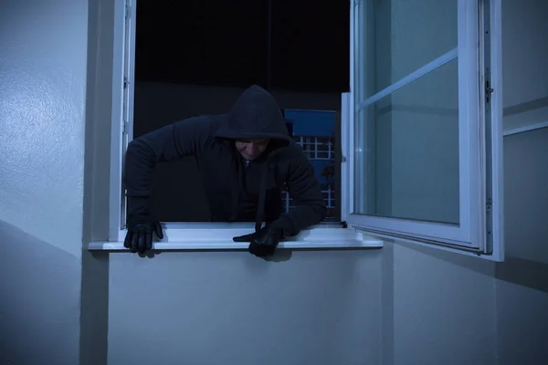 Inbrottstjuv kommer in genom fönstret — Stockfoto