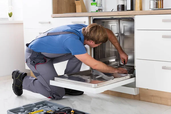 Ремонтник фіксує посудомийної машини — стокове фото