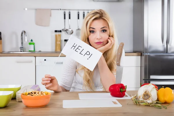 Mujer sosteniendo bandera de ayuda en la cocina — Foto de Stock