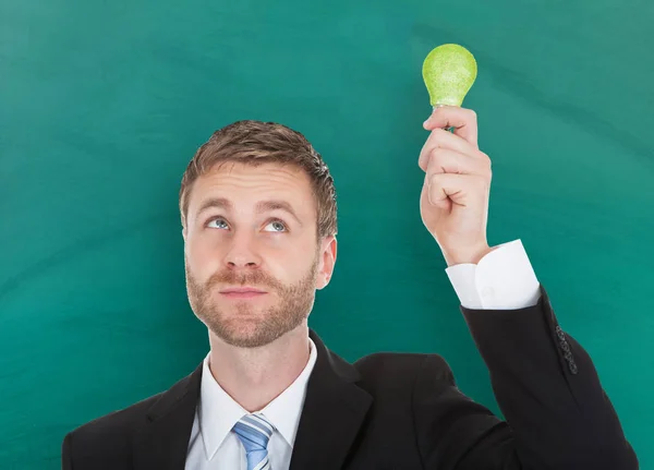 Uomo d'affari in possesso di lampadina ecologica — Foto Stock