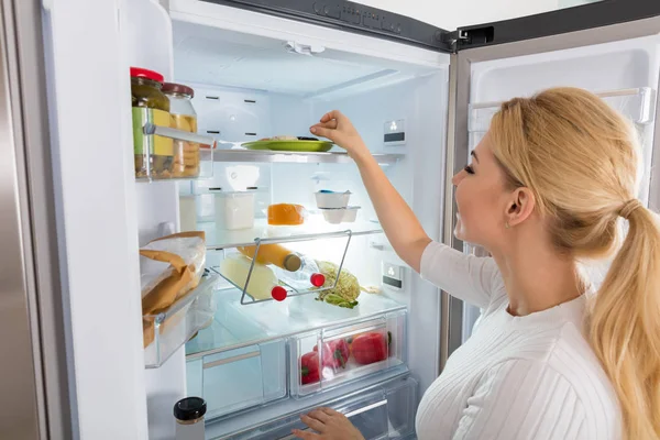 Mulher tomando alimentos da geladeira — Fotografia de Stock