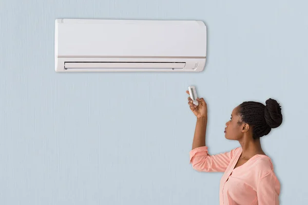 Woman using air conditioner — Stock Photo, Image